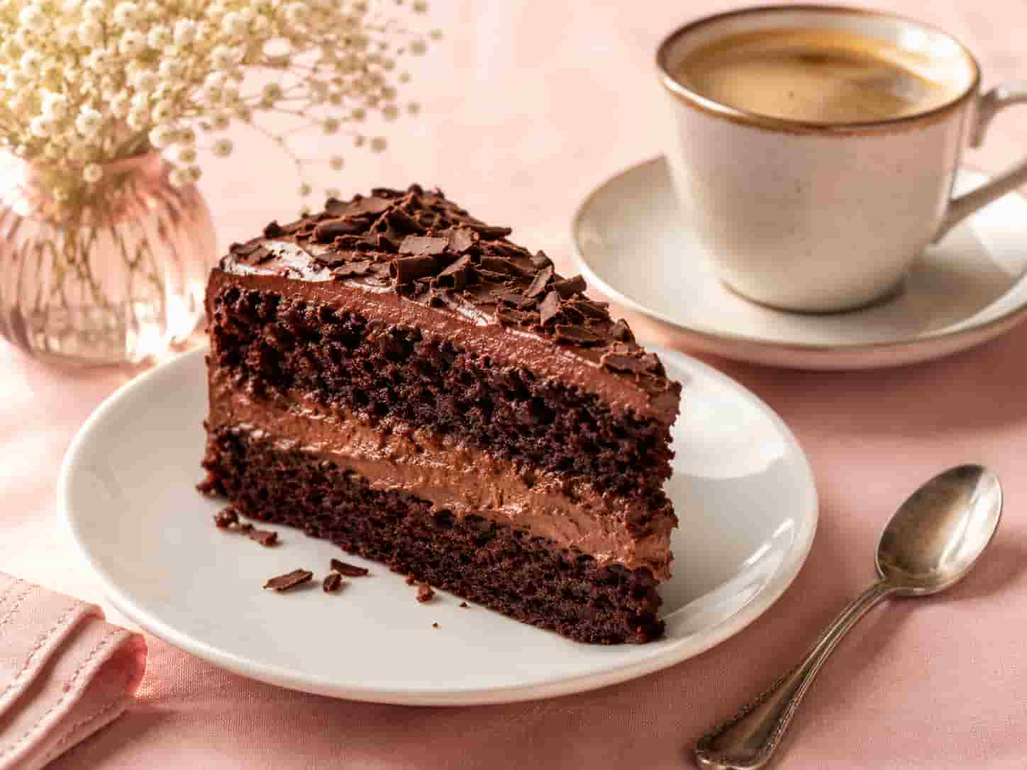 Stück Schokoladenschichttorte neben einer Tasse Kaffee