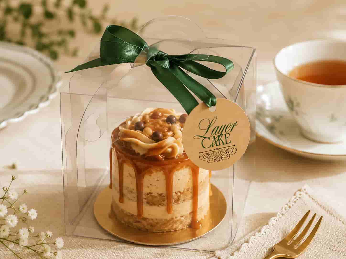Kleine Karamelltorte in einer Geschenkbox neben Tee